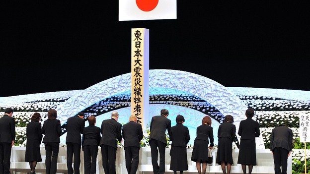 Relatives of earthquake and tsunami victims offer chrysanthemums during the national memorial service for the victims in Tokyo