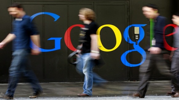 People walk past a logo next to the main entrance of the Google building in Zurich