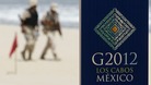 Soldiers walk near a sign of the G20 summit on a beach in Los Cabos 