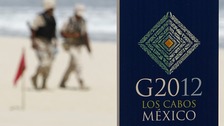 Soldiers walk near a sign of the G20 summit on a beach in Los Cabos 