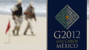 Soldiers walk near a sign of the G20 summit on a beach in Los Cabos 
