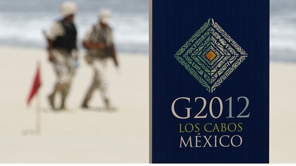 Soldiers walk near a sign of the G20 summit on a beach in Los Cabos