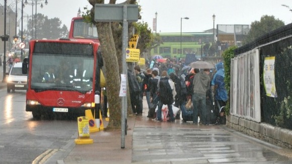 Music fans cue for the bus to get to the Isle of Wight Festival this morning.
