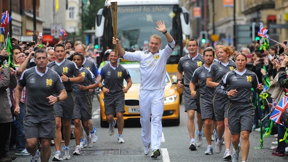 Sir Chris Hoy carrying the Olympic Flame on the Torch Relay leg between Higher Broughton and Manchester.