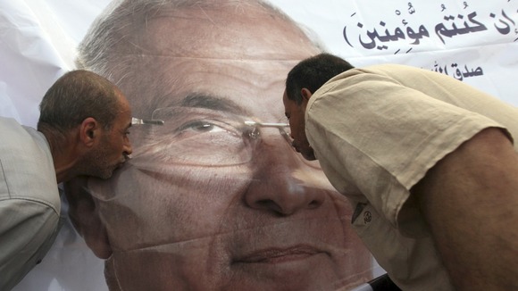 Supporters of former prime minister and presidential candidate Ahmed Shafik kiss his poster during a protest