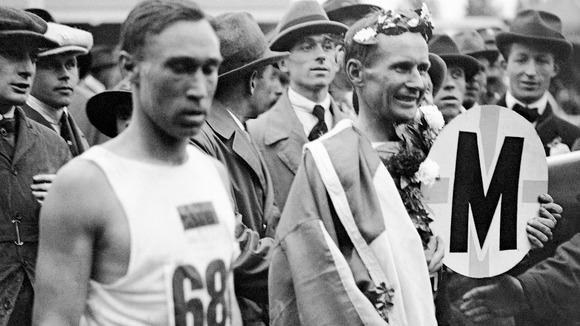Hannes Kolehmainen of Finland draped in the Finnish flag and crowned with a wreath of laurels after winning the Marathon in 1920