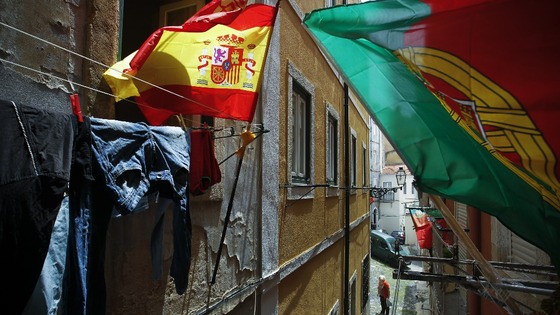 Portugal and Spain's flags wave at the balconies of a narrow street of Lisbon's Mouraria neighborhood.