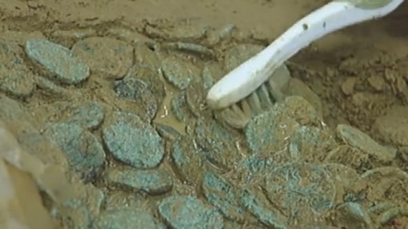 Archaeologists painstakingly examine the coins.