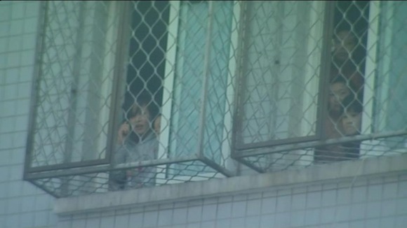 women looking out of a window of a 'black jail'