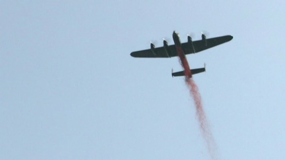 A Lancaster bomber flies past the Bomber Command memorial in London.
