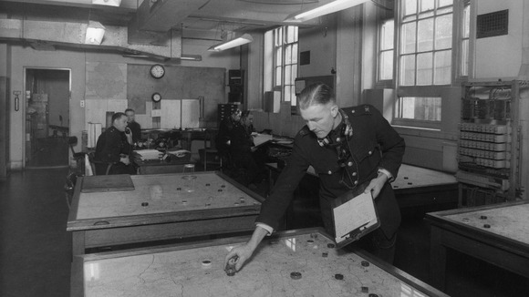 An officer in the Map Room identifying an available car after taking a 999 call.