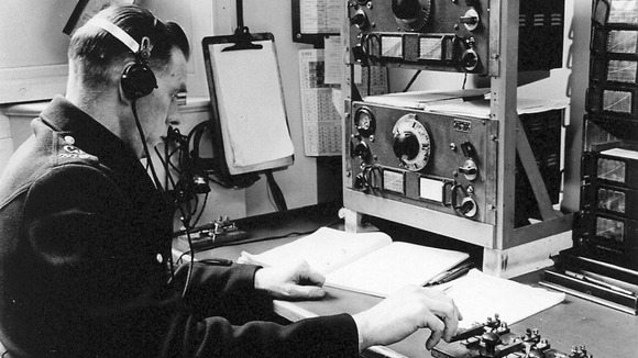 A radio dispatcher sending out messages in Morse Code to vehicles from the Information Room in the 1930s.