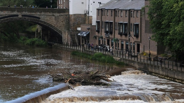 People look out over the fast flowing River Wear in Durham today after heavy rainfall in the area