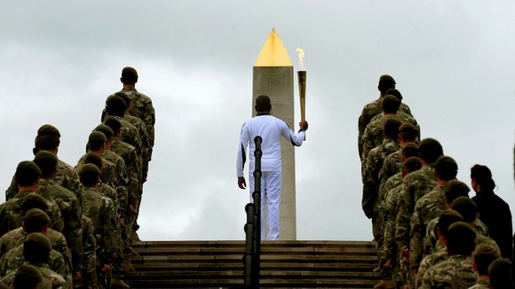 Corporal Johnson Beharry VC is flanked by soldiers as he carries the torch at the National Memorial Arboretum