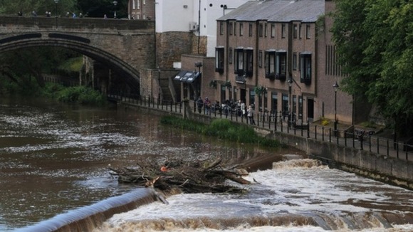 People look out over the fast flowing River Wear in Durham today after heavy rainfall in the area.