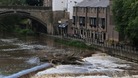 People look out over the fast flowing River Wear in Durham today after heavy rainfall in the area.