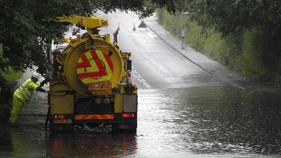 Council workers try to clear Manchester Road in Handforth, Cheshire after heavy rain caused flooding.