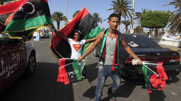 Libyan national flag sellers celebrate on the street after casting their vote