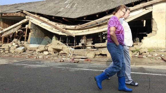 Local residents walk along a street damaged by floods in the town of Krymsk