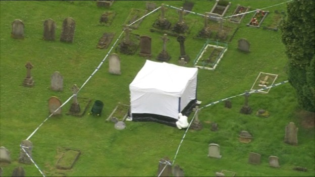 A forensic officer works in a cordon in the churchyard at All Saints Church in Writtle, Chelmsford.