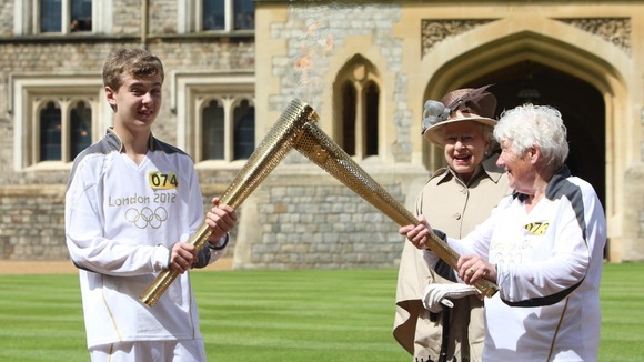 Gina Macgregor (right) passes the Olympic flame to torchbearer Phillip Wells.