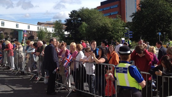 Crowds are ushered into place ahead of the Queen's arrival at the QE Hospital