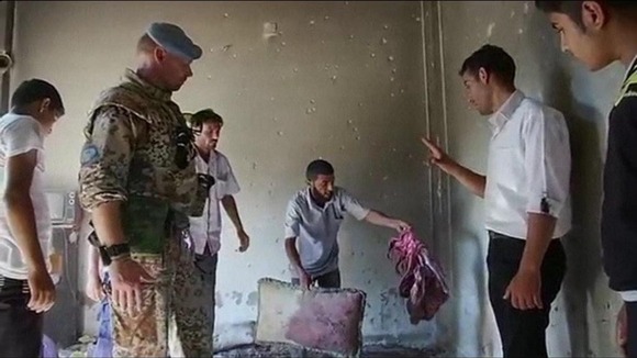 A resident in Tremseh shows an UN observer blood stained items in a house