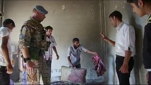 A resident in Tremseh shows an UN observer blood stained items in a house