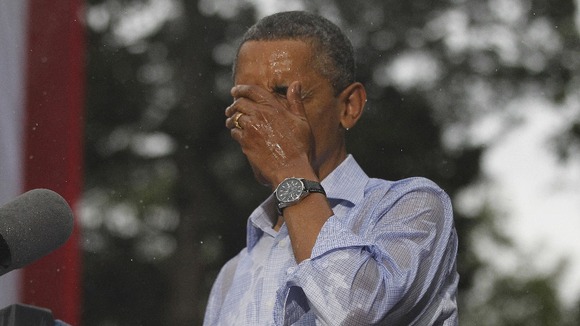 U.S. President Barack Obama wipes rain off his face during heavy rainfall at a campaign rally in Glen Allen