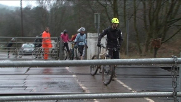 Cyclists being guided over the level crossing at Moors Gorse by a Network Rail worker