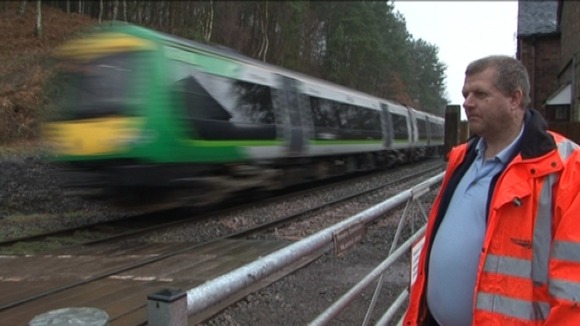 Network Rail worker closes barrier as London Midland train passes