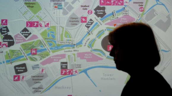 Theresa May stands in front of a map of the Olympic Park