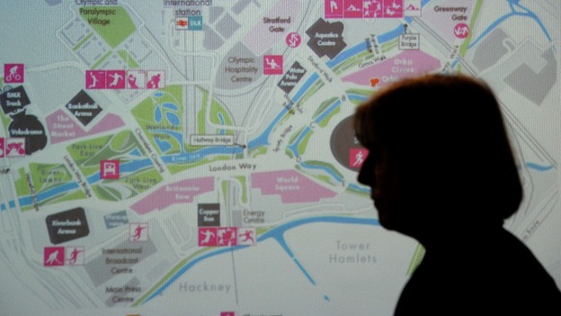 Theresa May stands in front of a map of the Olympic Park
