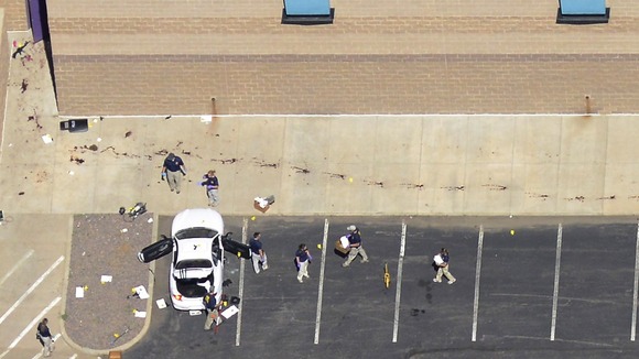 Police examine the car of Holmes behind the cinema.