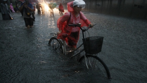 A woman cycles through the floodwater