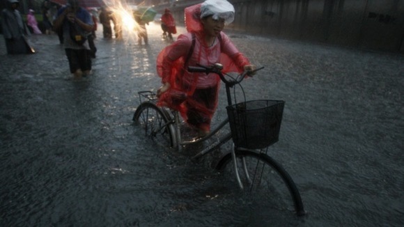 A woman cycles through the flood.