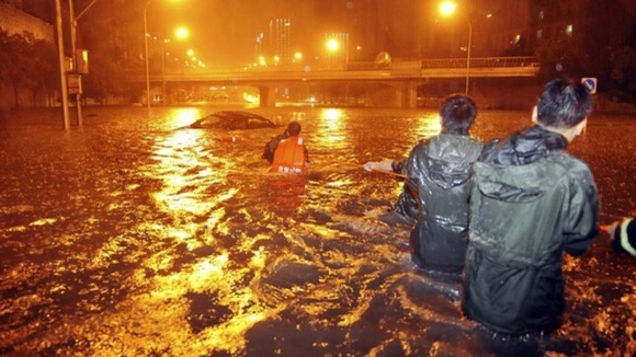 Rescuers try to pull a car from a flooded Beijing street.