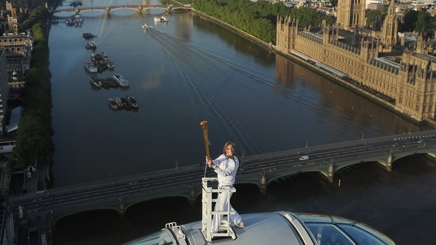 Amelia Hempleman-Adams poses with the Olympic Flame on top of a London Eye pod, with the Houses of Parliament behind her.