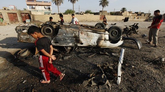 Residents gather at the site of a car bomb attack in Mahmudiya