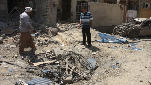 Residents inspect the site of a car bomb in the town of Taji