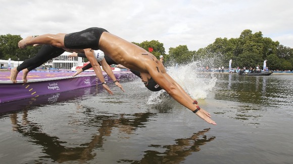 A marathon swimmer dives into the Serpentine lake in Hyde Park.