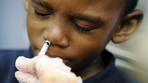 A boy is given flu vaccine in a nasal spray. 