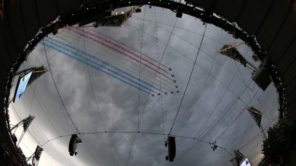 The Red Arrows leave coloured smoke trails as they fly over the Olympic Stadium