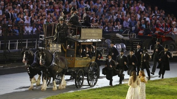 Performers run next to a horse-drawn wagon during the Opening Ceremony