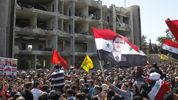 People gather at the site of the bomb attacks in Damascus today.