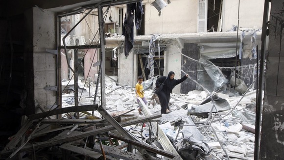 A woman walks through rubble from a building destroyed by shelling from forces loyal to Syrian President Bashar Al-Assad in downtown Aleppo