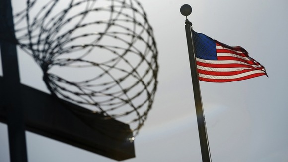 US flag flies above a razorwire-topped fence at the Camp Six detention facility