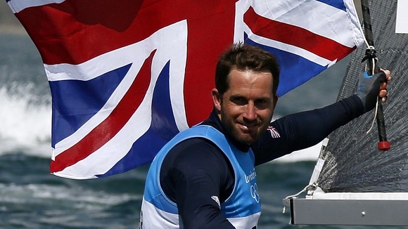 Ben Ainslie holds the Union Flag as he celebrates winning the men's finn class one person dinghy medal race sailing contest.