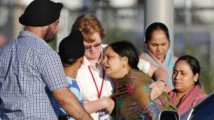 A distraught women is helped to a car outside of the Sikh temple in Oak Creek, Wisconsin.