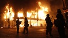 Police officers wearing riot gear stand in front of a burning building in Tottenham, north London August 7, 2011.